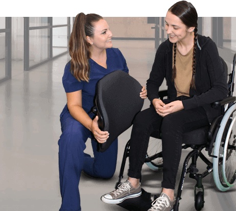 woman in wheelchair being assisted by woman holding a chair back